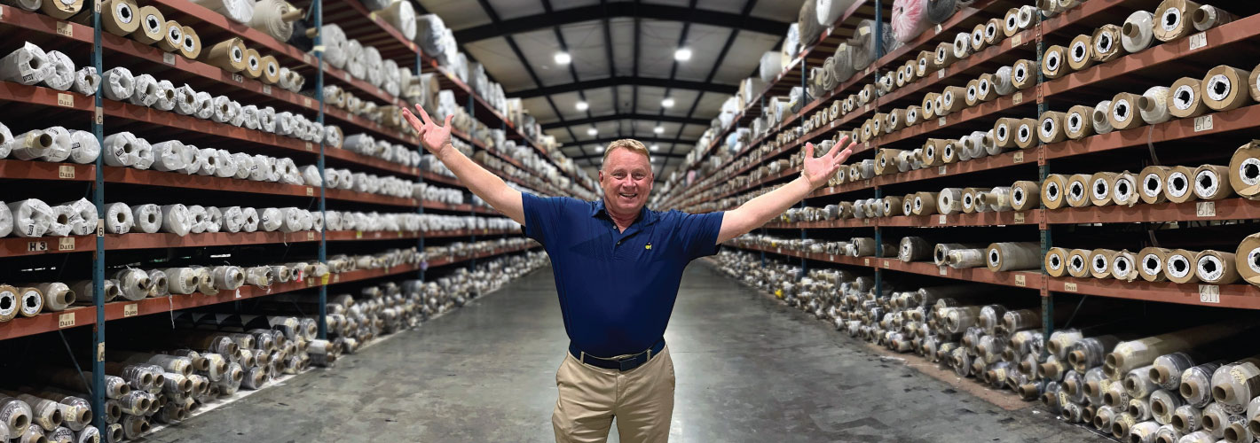 Carpet Express GM standing in front of Armstrong Sheet Vinyl Inventory in a Warehouse